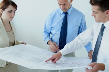 Photo for This here needs to be changed. a three businesspeople going over blueprints - Royalty Free Image