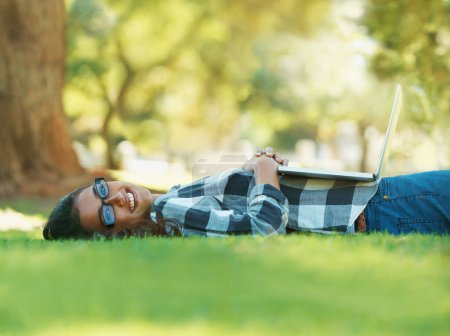 Téléchargez les photos : Se détendre avec un bon livre. une jeune femme allongée sur l'herbe et lisant un livre - en image libre de droit