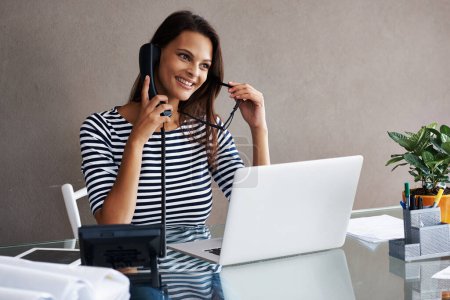 Foto de Sabe lo que necesitan sus clientes. una joven mujer de negocios hablando por teléfono mientras está sentada en el escritorio de su oficina - Imagen libre de derechos