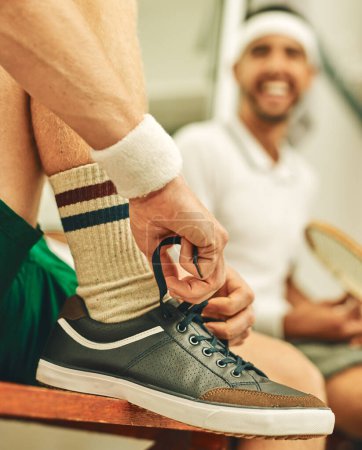 Foto de Usar los zapatos adecuados es crucial en una cancha de squash. un hombre poniéndose sus zapatillas en el vestuario antes de un partido de squash - Imagen libre de derechos