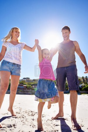 Téléchargez les photos : Bon temps sur la plage. une jeune famille heureuse faisant une promenade sur la plage - en image libre de droit