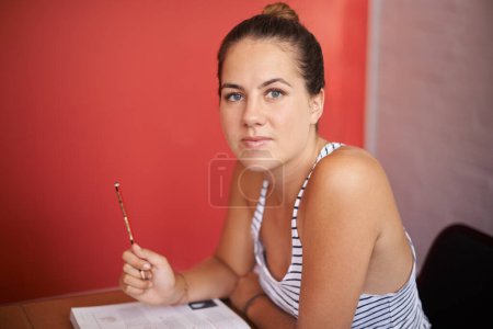 Téléchargez les photos : Je suis un peu bourré. Portrait d'une jeune étudiante assise à son bureau dans une salle de classe - en image libre de droit