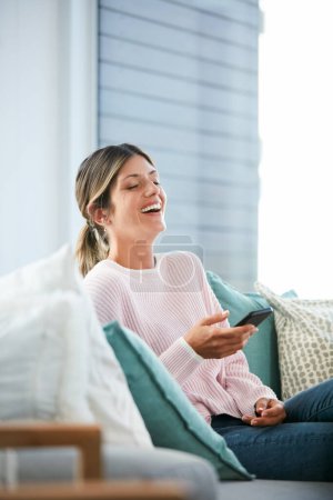 Photo for I cant go a day without my memes. an attractive woman using her cellphone while relaxing at home - Royalty Free Image