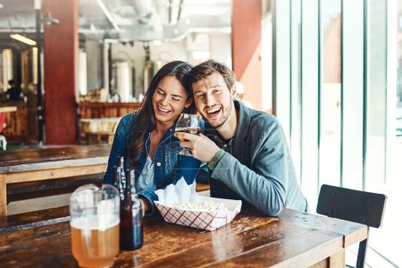 Téléchargez les photos : On va ensemble comme vendredi et happy hour. un jeune homme et une jeune femme heureux qui boivent des bières dans un bar - en image libre de droit