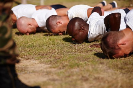Foto de Empuja al límite en el campo de entrenamiento. un grupo de hombres haciendo flexiones en un campo de entrenamiento militar - Imagen libre de derechos