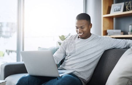 Photo for Black man with laptop, streaming online and relax in living room, subscription service with internet and happiness. Technology, connectivity and male person chill at home watching movie on sofa. - Royalty Free Image