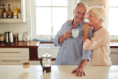 Téléchargez les photos : Ils sont liés à cœur. un couple de personnes âgées affectueux dans la cuisine - en image libre de droit