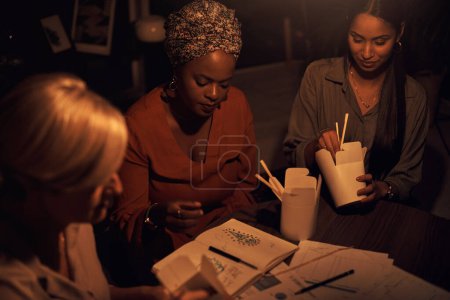 Photo for Having some takeout to fuel their late night. a group of businesswomen eating takeout while working together in an office at night - Royalty Free Image