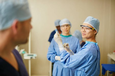 Photo for Getting ready to save lives. surgeons putting on surgical gloves in preparation for a surgery - Royalty Free Image