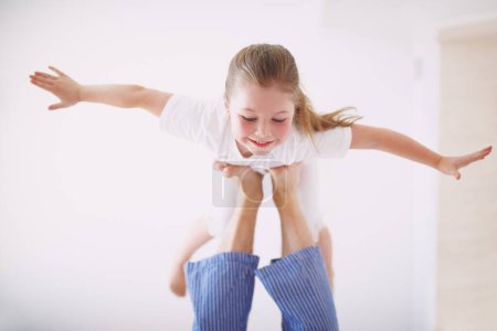 Photo for Look I can fly. A young girl propped up on her fathers feet with her arms outstretched - Royalty Free Image
