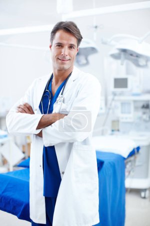 Foto de El médico que esperas. Un médico varón feliz de pie con los brazos cruzados en el quirófano - Imagen libre de derechos