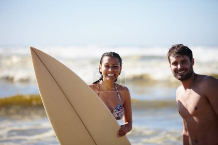 Téléchargez les photos : J'adore les eaux d'été. Portrait d'un jeune couple heureux posant avec une planche de surf dans la mer - en image libre de droit