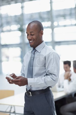 Photo for Great news, I got the deal. A handsome african businessman, text messaging and smiling - Royalty Free Image