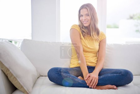Téléchargez les photos : Qui n'aime pas un week-end paresseux. Portrait d'une jolie jeune femme assise sur le canapé à la maison - en image libre de droit