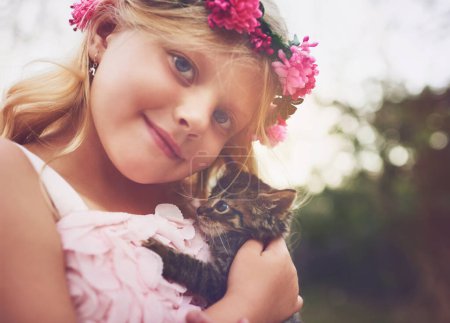Foto de Eres pequeño como yo. una niña feliz sosteniendo un gatito y mirando a la cámara exterior en la naturaleza - Imagen libre de derechos