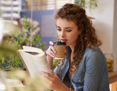 Foto de Relajarse con un buen libro. una joven leyendo un libro en una cafetería - Imagen libre de derechos