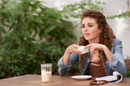 Téléchargez les photos : Détente avec une tasse de café frais. une jeune femme buvant du café dans un café - en image libre de droit