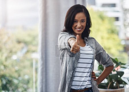 Photo for Thumbs up to the weekend. Portrait of a young woman showing thumbs up at home - Royalty Free Image