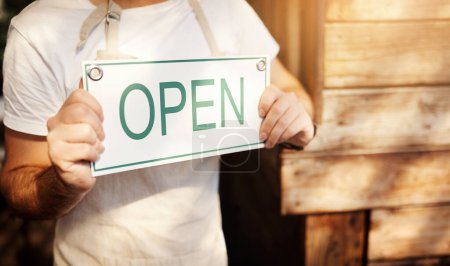 Téléchargez les photos : Ouvert aux affaires. un propriétaire d'entreprise méconnaissable brandissant une pancarte à la porte de son café - en image libre de droit