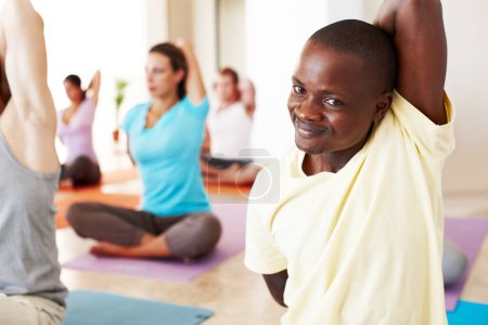 Téléchargez les photos : Prendre plaisir au yoga. Un jeune Africain qui fait des étirements en cours de yoga - en image libre de droit