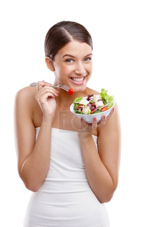 Téléchargez les photos : Délicieuse fraîcheur. Portrait d'une belle jeune femme debout avec un bol de salade sur fond blanc - en image libre de droit