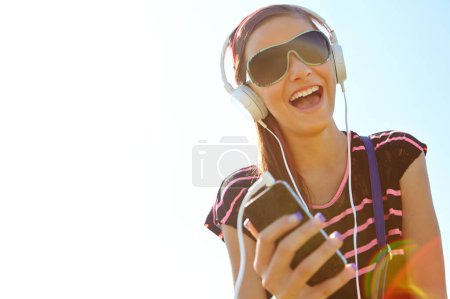 Foto de Esta es mi canción. Una joven adolescente feliz escuchando música por sus auriculares - Imagen libre de derechos
