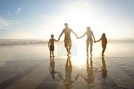 Photo for Summer silhouettes. a young family walking on a beach at sunset - Royalty Free Image