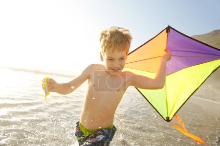 Téléchargez les photos : Profitant de son nouveau cerf-volant à la plage. un petit garçon courant tout en tenant un cerf-volant sur une plage - en image libre de droit