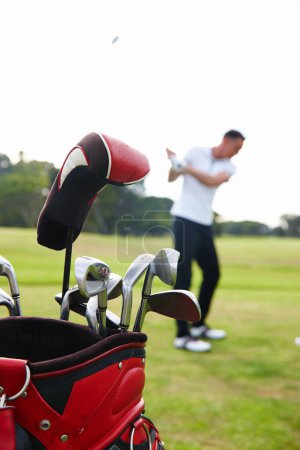 Téléchargez les photos : C'est juste toi et le jeu. un sac de golf avec un homme jouant au golf en arrière-plan - en image libre de droit