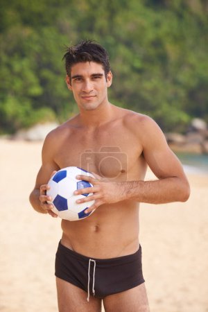 Photo for Soccer anyone. A portrait of a handsome young man with a soccer ball on the beach - Royalty Free Image