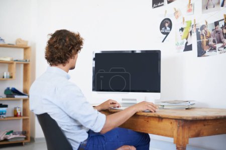 Photo for Working with zero distractions. Rearview shot of a young man working on a computer - Royalty Free Image