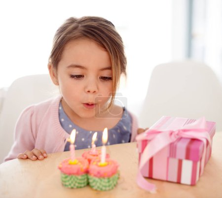 Téléchargez les photos : C'est mon anniversaire. une jeune fille soufflant les bougies sur ses cupcakes d'anniversaire - en image libre de droit
