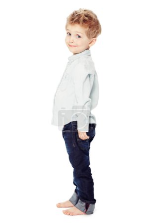 Téléchargez les photos : Mignon, sourire et portrait d'un enfant à la mode isolé sur fond blanc dans un studio. Adorable, heureux et un petit garçon comme modèle de vêtements en jeans pour les jeunes avec bonheur et sourire. - en image libre de droit
