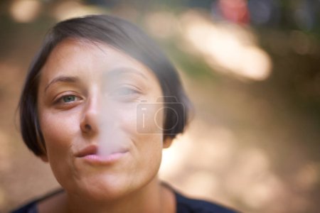Téléchargez les photos : Je passe un bon moment. Portrait d'une femme soufflant de la fumée de sa bouche - en image libre de droit