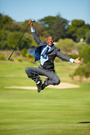 Téléchargez les photos : Homme, golf et saut pour la célébration, visage excité ou portrait pour gagner, réalisation ou but en plein air. Homme d'affaires africain, golfeur et vainqueur d'entreprise au terrain de sport avec costume, liberté ou fitness. - en image libre de droit