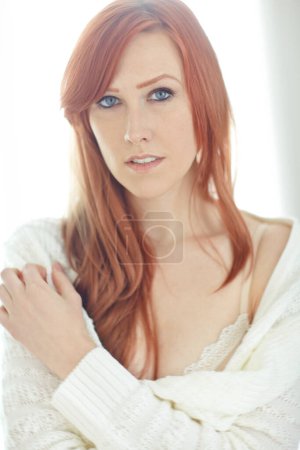 Photo for Portrait of one beautiful young redhead woman relaxing on a bed at home. Confident female feeling flirty, sensual and sexy while posing seductively in unbuttoned white shirt and underwear. - Royalty Free Image