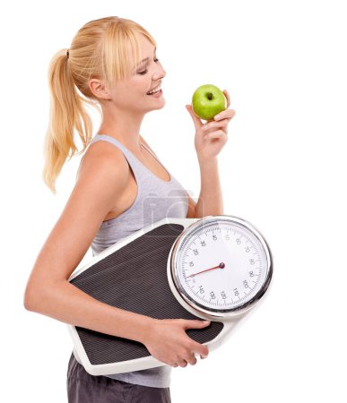 Photo for Weight-loss through healthy eating. A woman holding a scale and eating an apple - Royalty Free Image