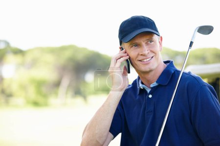 Foto de Estoy en el sexto hoyo. un hombre parado en un campo de golf y hablando por su celular - Imagen libre de derechos