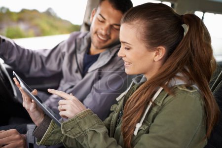 Téléchargez les photos : Vous avez les coordonnées. un jeune couple vérifiant son GPS lors d'un road trip - en image libre de droit