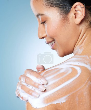 Foto de Dándole a mi piel el amor que merece. una atractiva joven que usa un gel de baño mientras se ducha sobre un fondo azul - Imagen libre de derechos