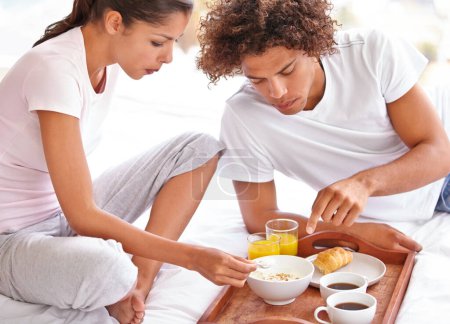 Téléchargez les photos : Tu commences bien la journée. un jeune couple heureux en train de prendre le petit déjeuner au lit depuis un plateau - en image libre de droit
