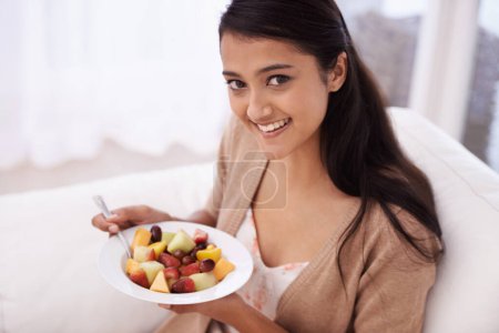 Photo for Packed with vitamins. A beautiful young woman enjoying a healthy snack from the comfort of her couch - Royalty Free Image