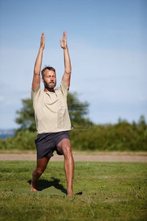 Photo for Focused while going through his posture sequence. Full length shot of a handsome mature man doing yoga outdoors - Royalty Free Image