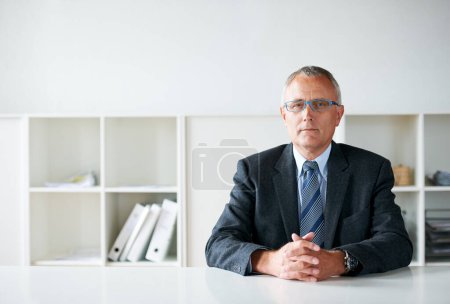 Téléchargez les photos : Face cachée du monde des affaires. un homme d'affaires senior assis à une table - en image libre de droit