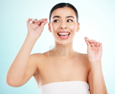 Foto de Una sonrisa perfecta requiere trabajo. Foto de estudio de una joven atractiva usando hilo dental sobre un fondo claro - Imagen libre de derechos
