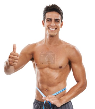 Photo for Keeping fit and positive. Portrait of a handome muscular man measuring his torso with a measuring tape and showing thumbs up against a white background - Royalty Free Image