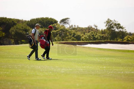 Téléchargez les photos : Plus qu'un trou. deux hommes portant leurs sacs de golf sur un terrain de golf - en image libre de droit