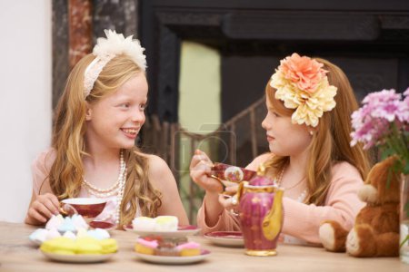 Photo for Its tea time. Two friends dressing up and having a tea party outside in the garden - Royalty Free Image