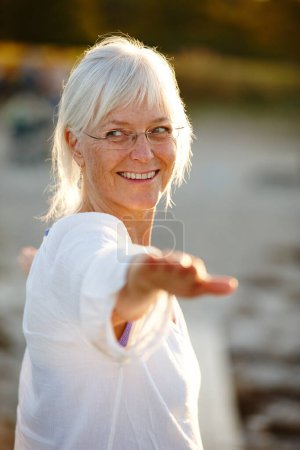 Photo for Enjoying her daily yoga workout. an attractive mature woman doing yoga on the beach at sunset - Royalty Free Image