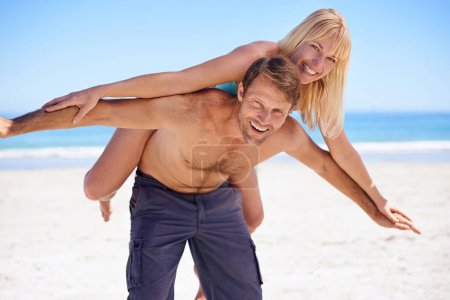 Photo for Care-free and committed. A handsome husband playfully carrying his wife on the beach - Royalty Free Image